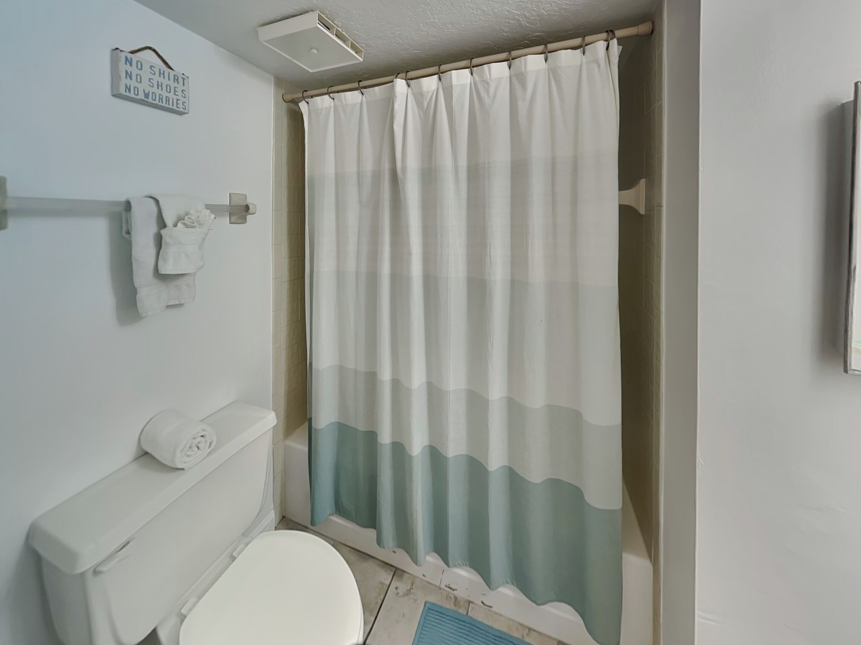 Une salle de bain équipée de toilettes, d’un porte-serviettes et d’un rideau de douche.