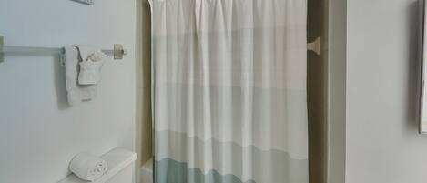 Une salle de bain équipée de toilettes, d’un porte-serviettes et d’un rideau de douche.
