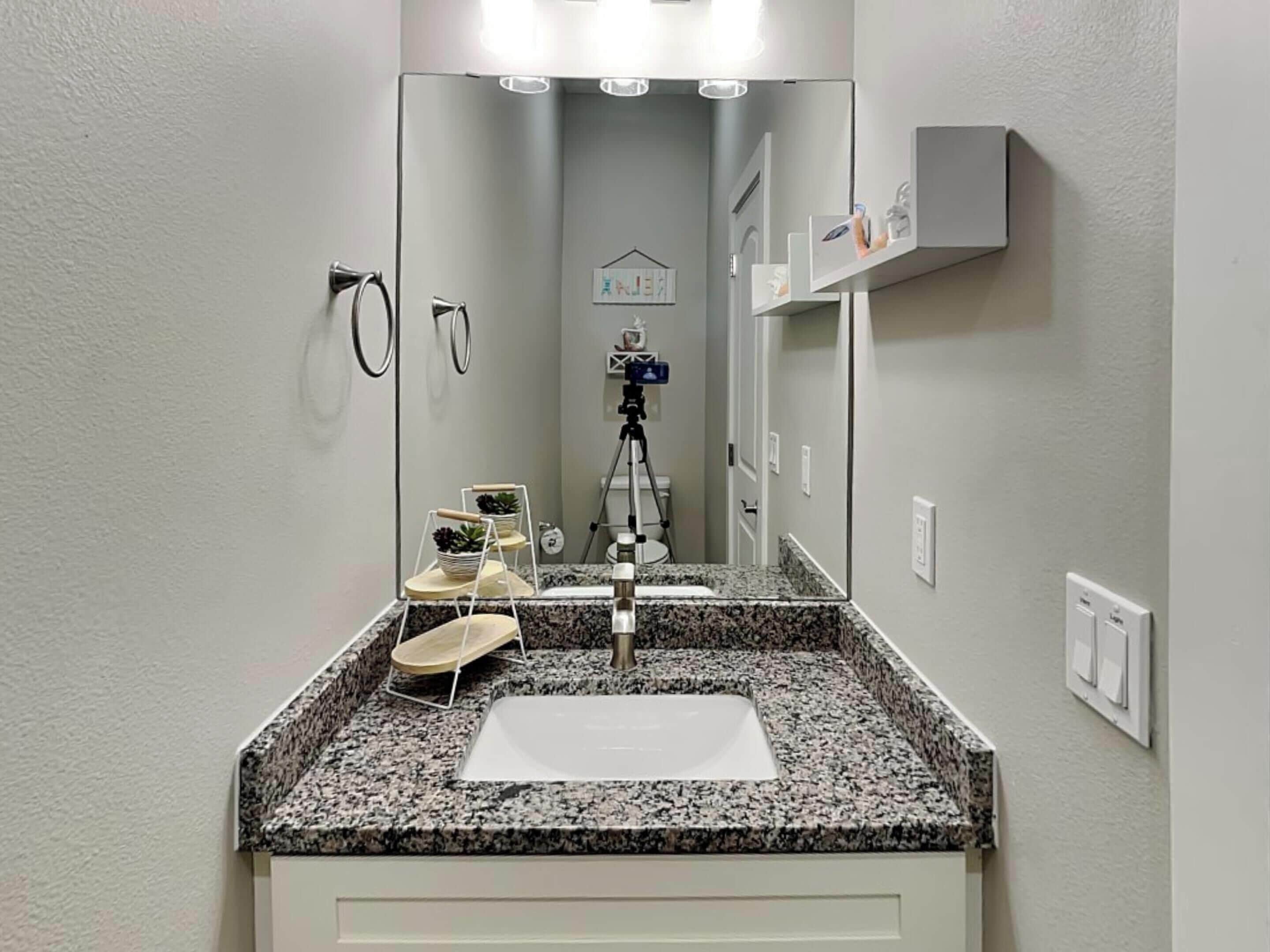 A bathroom with a granite countertop, a white sink, and a mirror.