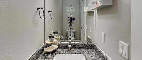 A bathroom with a granite countertop, a white sink, and a mirror.