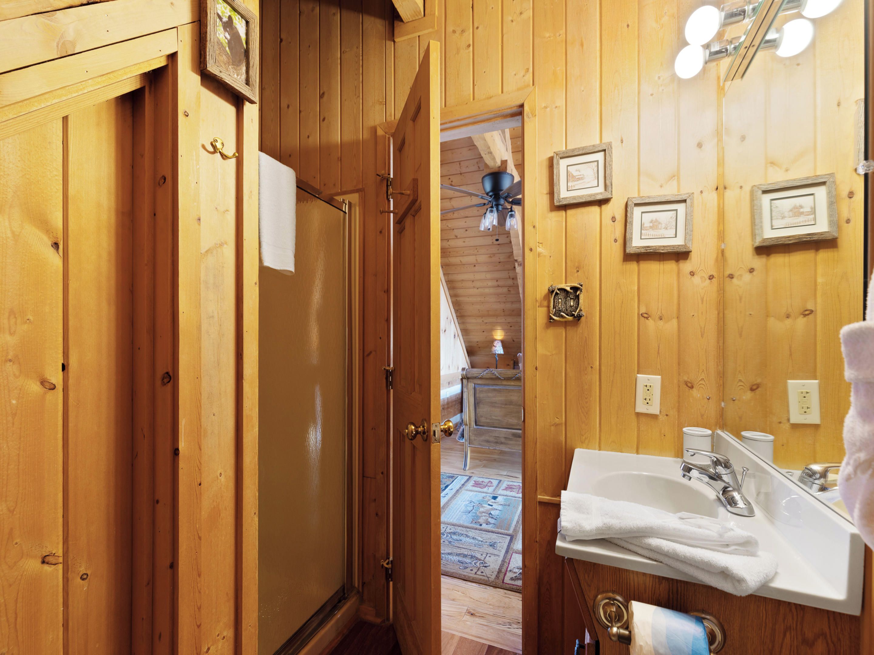 A wooden bathroom with a sink, mirror, and towel rack.