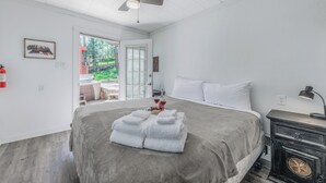 Una camera da letto con un letto, un comodino, un termosifone, una ventola a soffitto e vista sull'esterno.