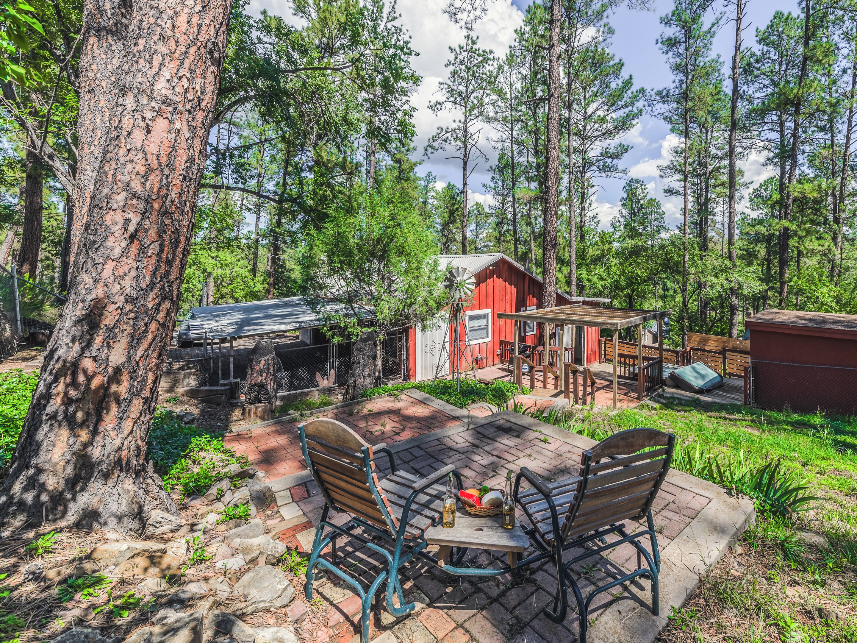 A rustic cabin with a brick patio, wooden deck, and a windmill.