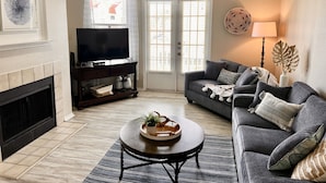 A living room with a fireplace, a television, a sofa, and a coffee table. - Toes In The Water II by Silver Sands Vacation Rentals (Corpus Christi)