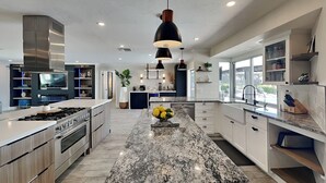 A modern kitchen with a central island, stainless steel appliances, and pendant lighting. - Nauti Mermaid by Distinctive Beach Rentals (Cape Coral)