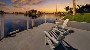 A waterfront view with a dock, chairs, and an obelisk. - Nauti Mermaid by Distinctive Beach Rentals (Cape Coral)