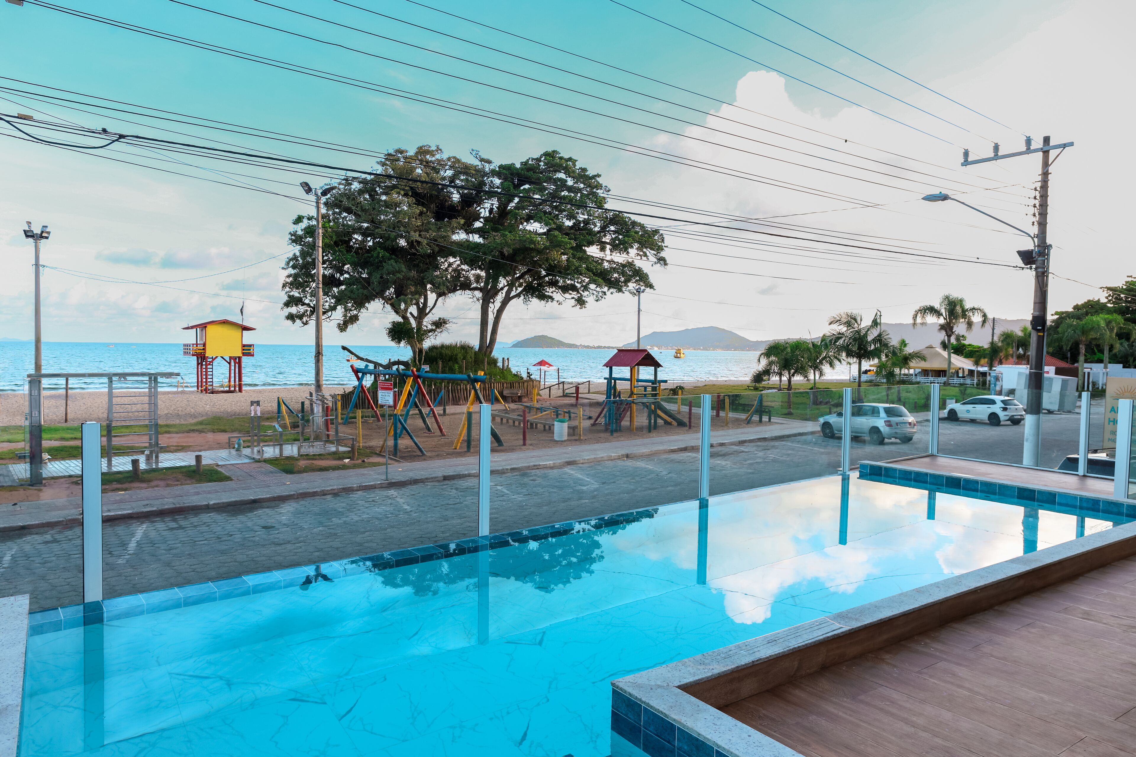 A swimming pool with a view of the beach and playground equipment.