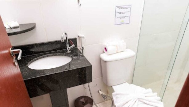 Un baño con un lavabo negro, inodoro blanco y cabina de ducha de cristal.