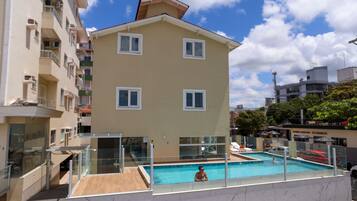Un edificio residencial con piscina, balcones y cielo despejado.