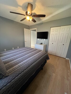 A bedroom with a bed, a ceiling fan, a TV mounted on the wall, and a wardrobe. - Relaxing lake front home with beautiful view on the lake, sleeps 7.  (Creal Springs)