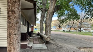 A building with a covered porch, a gravel pathway, and a fence in the background. - Cozy Queen with Kitchenette in Flaming Gorge (Manila)
