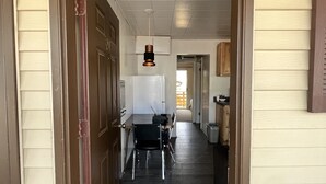 A hallway with a dark wooden floor, a white refrigerator, and a dining table with chairs. - Cozy Queen with Kitchenette in Flaming Gorge (Manila)