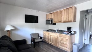 A compact living space with a sofa, a chair, a kitchenette, and a trash bin. - Cozy Queen with Kitchenette in Flaming Gorge (Manila)