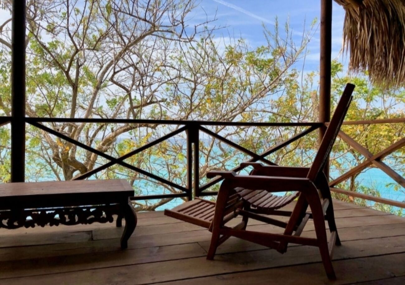 Une terrasse en bois avec une rambarde en métal, un banc et une table.
