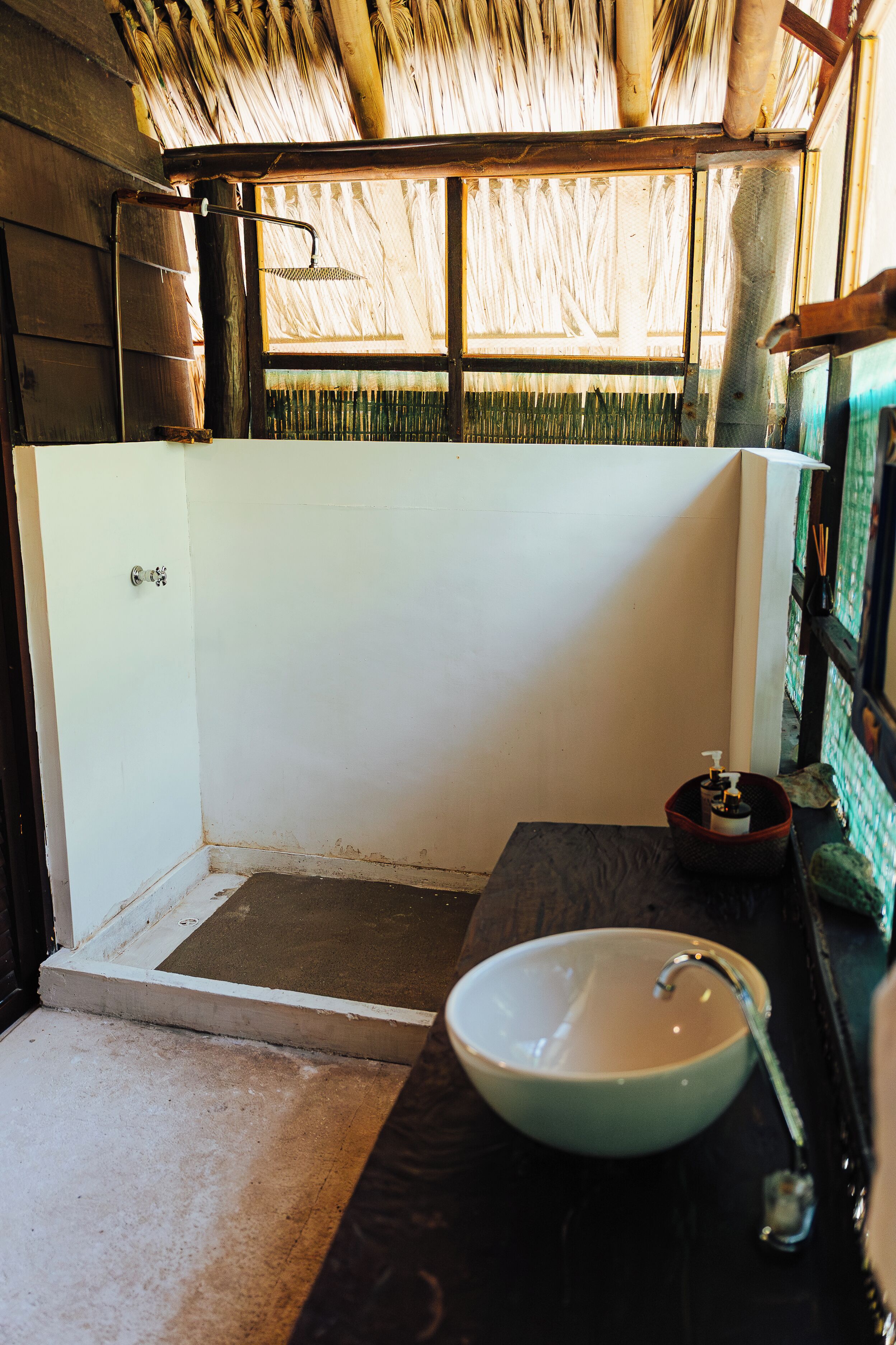 A bathroom with a white sink, a shower, and a wooden ceiling.