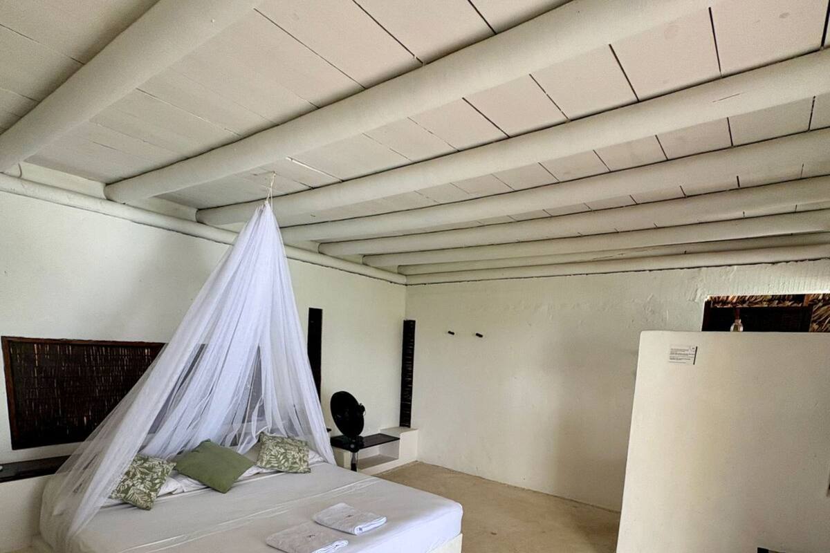 A bedroom with a bed under a canopy, a bedside table, and a wardrobe.