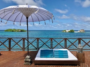 A wooden deck with a bed, an umbrella, and a view of the ocean. - Isla Unica - Islas del Rosario (Rosario Islands)