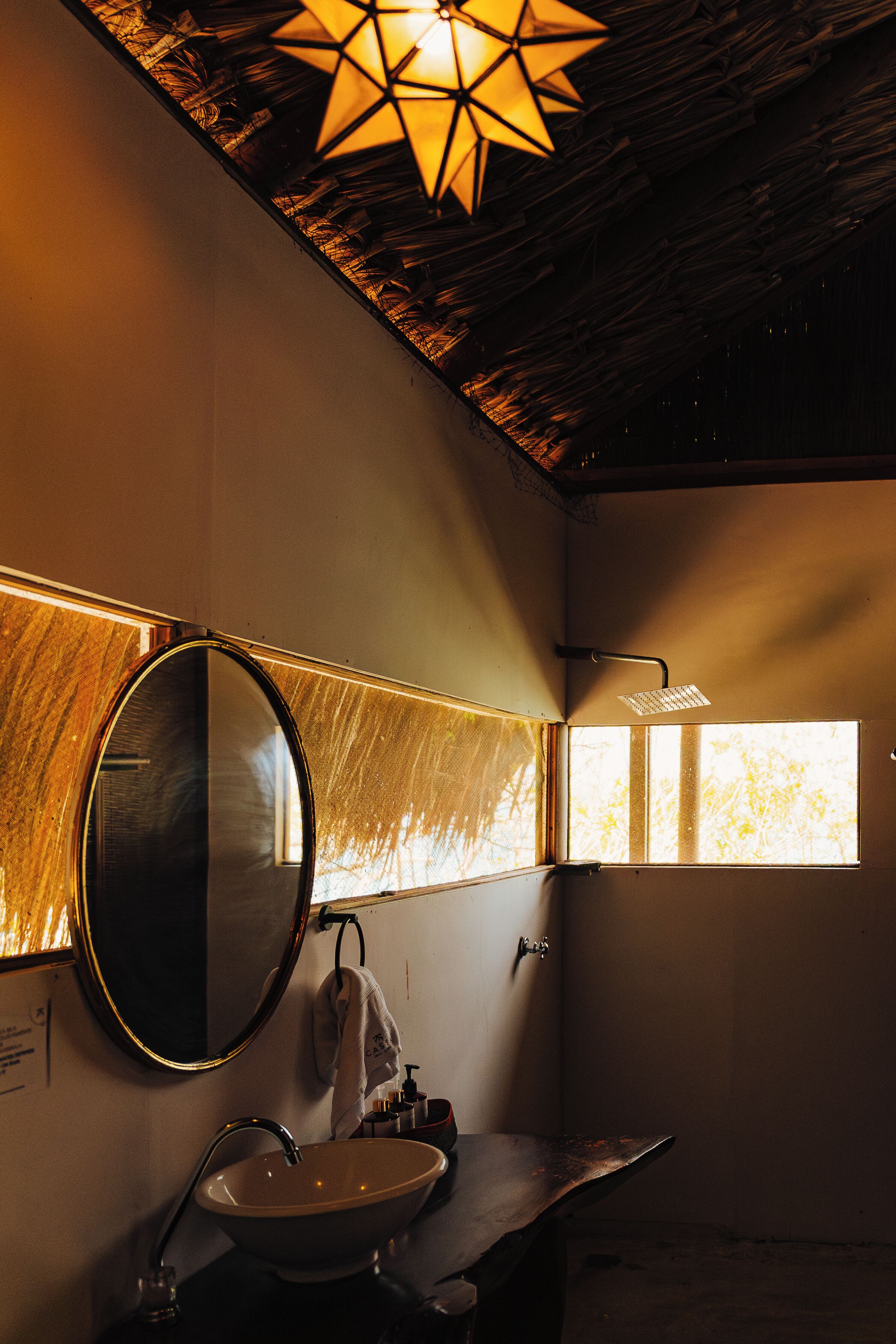 Een badkamer met een ronde spiegel, een wastafel en een douche.
