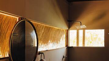 Een badkamer met een ronde spiegel, een wastafel en een douche.