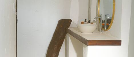 Een badkamer met een witte wastafel, een spiegel en een houten deur.