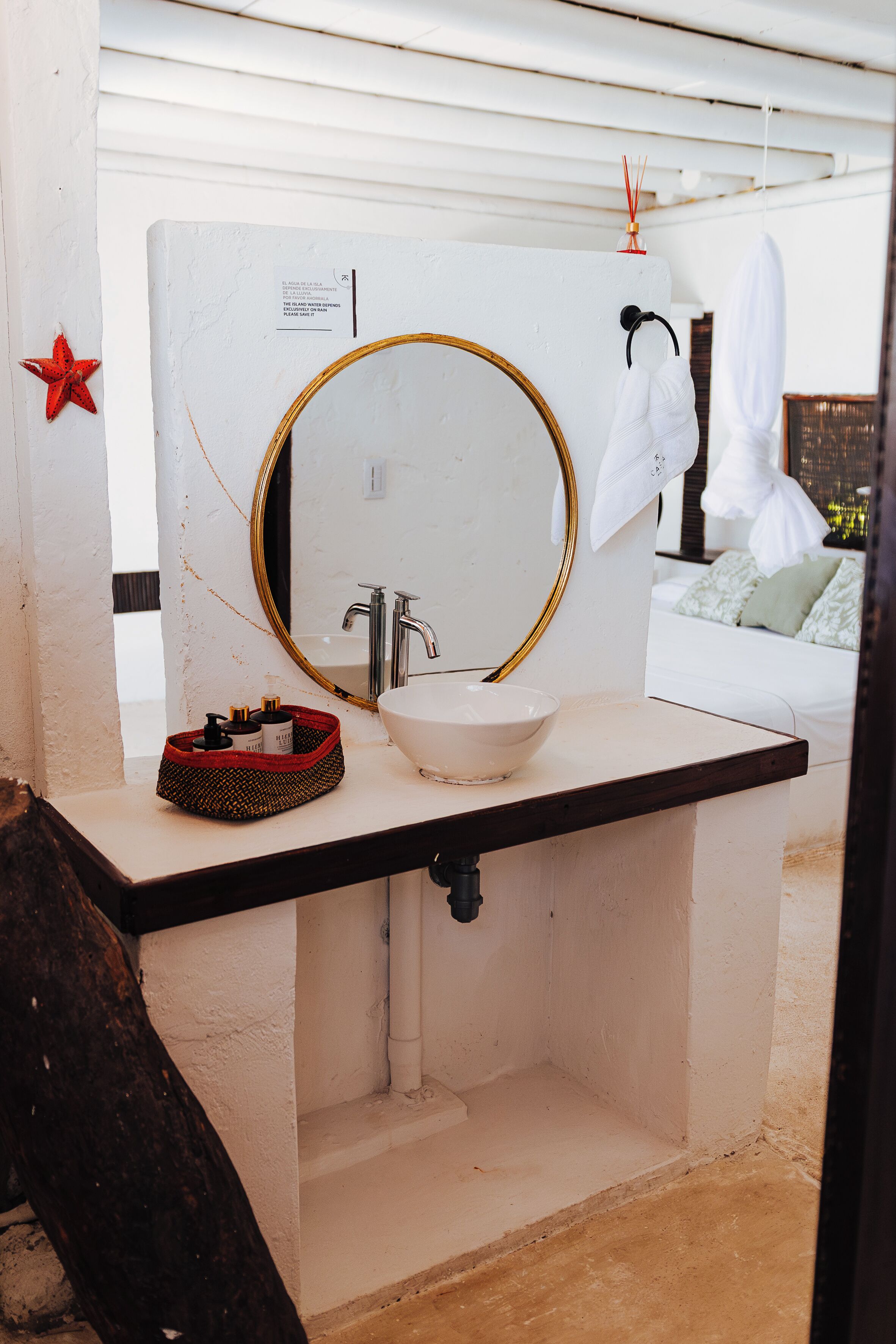 Un bagno con un lavandino bianco, uno specchio con cornice dorata e una decorazione a forma di stella rossa sul muro.