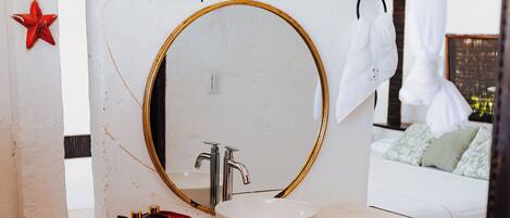 Un bagno con un lavandino bianco, uno specchio con cornice dorata e una decorazione a forma di stella rossa sul muro.