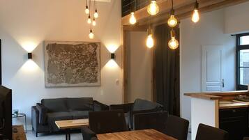 Een moderne keuken met houten kastjes en een aanrecht, een eethoek met een houten tafel en stoelen, en een zithoek met een bank en salontafel.