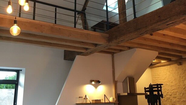 Een loft-achtige ruimte met zichtbare houten balken, een keukenhoek en een eethoek.