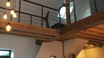 Een loft-achtige ruimte met zichtbare houten balken, een keukenhoek en een eethoek.