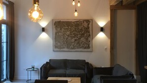 Een moderne woonkamer met een houten plafond, een groot abstract schilderij en een eethoek met een houten tafel en stoelen.