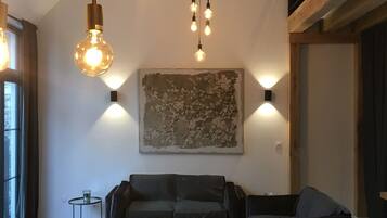 Een moderne woonkamer met een houten plafond, een groot abstract schilderij en een eethoek met een houten tafel en stoelen.