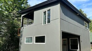 A two-story building with a garage door, large windows, and a sloped roof. - Ski, Bike and family fun at "The Future" cottage.  (Jay)