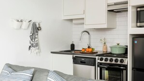 A modern kitchen with white cabinets, a stove, a sink, and a refrigerator. - * NEW * - The Marigold: Private Balcony | Walkable (Atlanta)