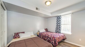 Una camera da letto con due letti, una finestra con tende a motivi e una luce a soffitto.