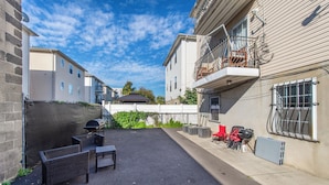 Un cortile con posti a sedere all'aperto, un barbecue e un edificio con un balcone.