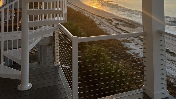 A spiral staircase leading to a balcony overlooking a beach at sunset. - SandyFeet Beach House Retreat-Gulf Front Home at Shell Point Beach.  (Crawfordville)