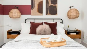A modern bedroom with a bed, two nightstands, a wall-mounted lamp, and abstract artwork. - ~The Abigail~ Rooftop / Skyline / Cozy (Atlanta)