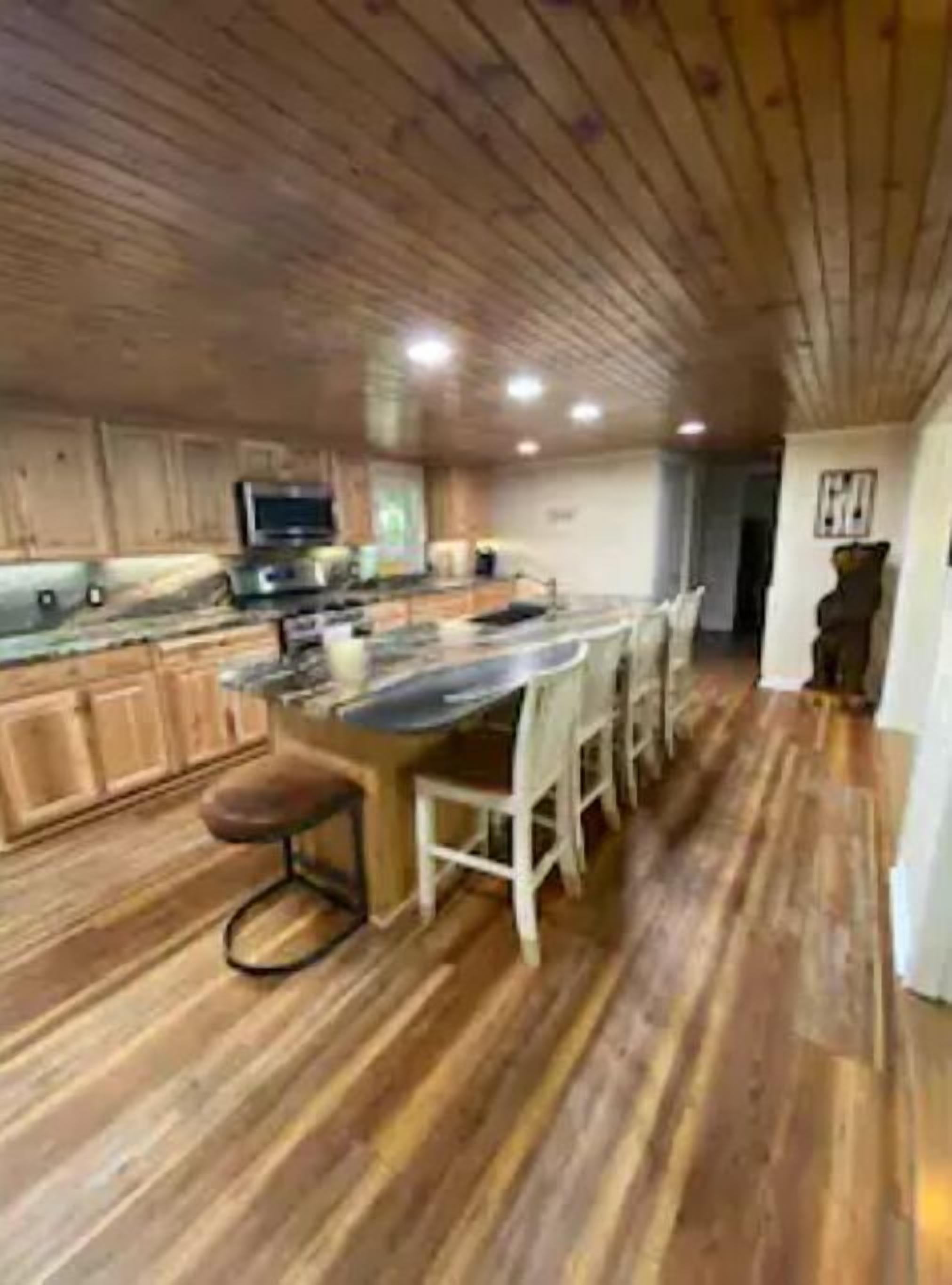 Una cocina moderna con armarios de madera, una isla central con taburetes y un horno empotrado.