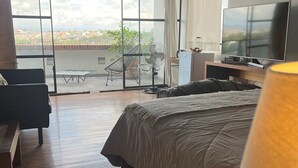 Una camera d'albergo con un letto, una scrivania, una sedia, una televisione e un balcone con vista.