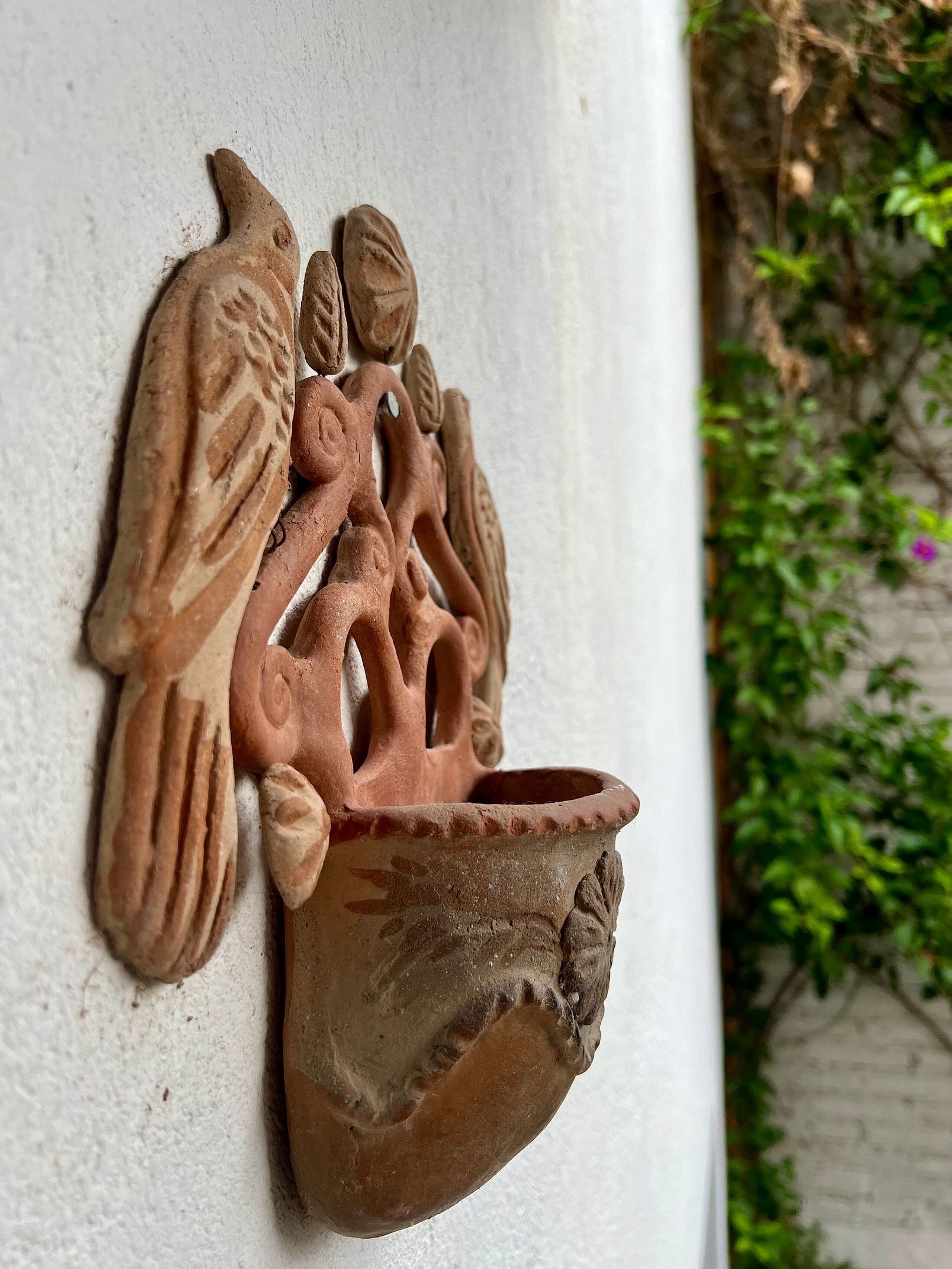 Una escultura de arcilla en la pared, representando una figura humana alada.