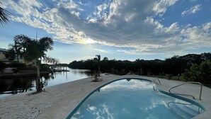 A swimming pool with a view of a calm body of water and a cloudy sky.