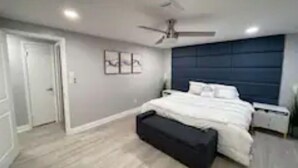A bedroom with a bed, a ceiling fan, a nightstand, and a bench.