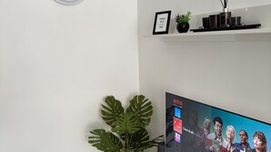 A modern living room with a flat-screen TV, a clock, a potted plant, and a shelf with decorative items. - Schön, Modern und Ruhige Lage. Nah am Zentrum Perfekt für 4. Parking, Netflix (Arona)