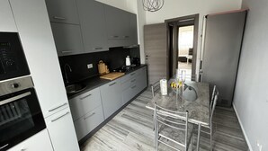 A modern kitchen with grey cabinets, a built-in oven, and a dining area with a marble table and metal chairs. - Schön, Modern und Ruhige Lage. Nah am Zentrum Perfekt für 4. Parking, Netflix (Arona)