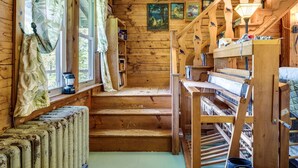 Interior rústico de cabana com paredes de madeira, escada, cama de madeira e janela com cortinas.