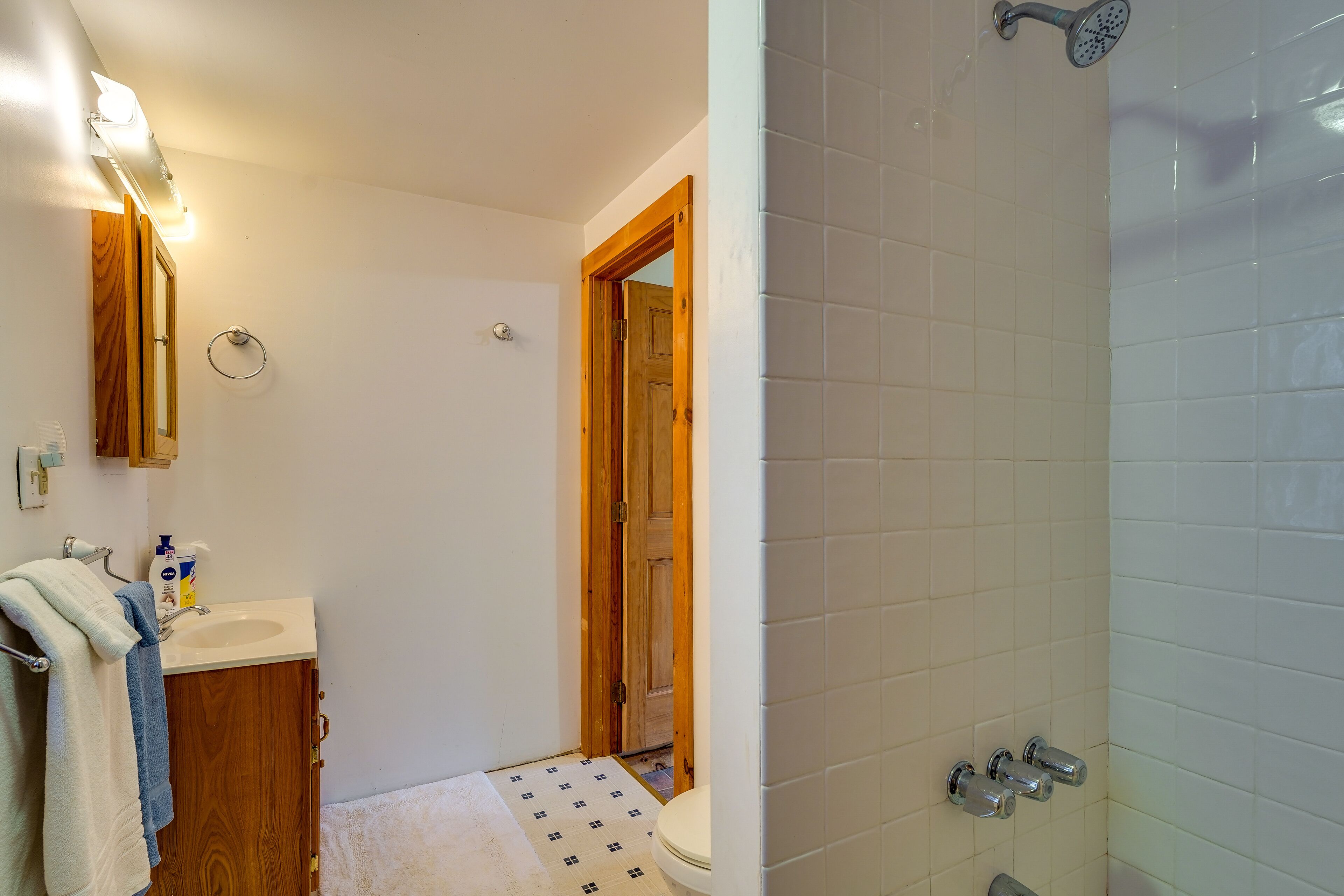 Een badkamer met een houten deur, een wastafel met spiegel en een douche.