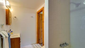 Een badkamer met een houten deur, een wastafel met spiegel en een douche.