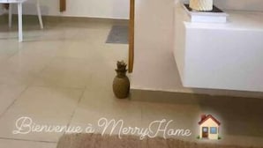 A minimalist living room with a white sofa, a small table, and a decorative vase. - Merryhome, Studio Avec bcp de Charme (Abidjan)