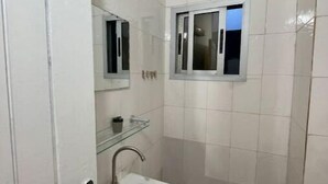 A small bathroom with a white sink, a mirror, and a shower. - Merryhome, Studio Avec bcp de Charme (Abidjan)