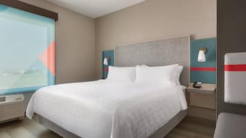 A hotel room with a large bed, a nightstand with a phone, and a window with a view.